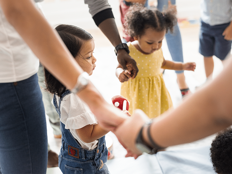 caregivers and children holding hands in a circle